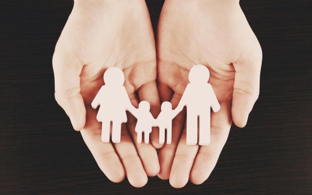 Female hands with family model on dark wooden background
