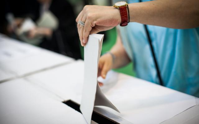Hand of a person casting a ballot at a polling station during voting