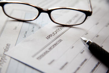 A pair of glasses abd a pen on empty application forms